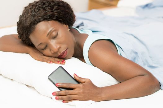 Beautiful woman sleeping in bed with her cell phone in her hand