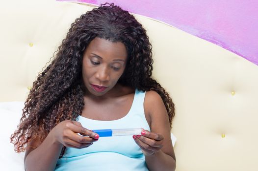 photo of sick mature woman sitting in bed testing its temperature with a thermometer