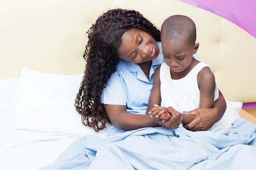 Mum comforting her son in tears sitting in bed with her.