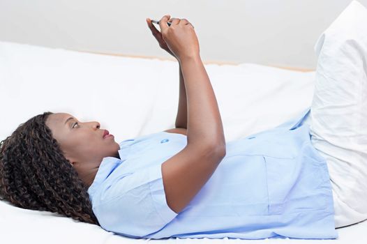 young woman lying on the bed using a smart phone at home