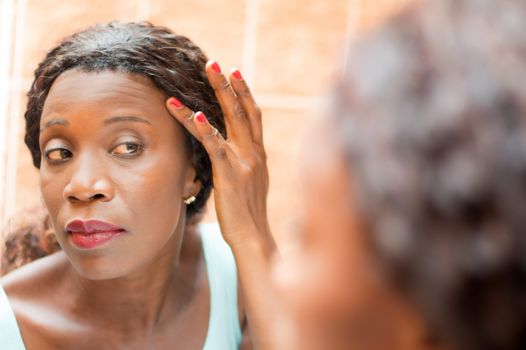 young woman looks in the mirror in order to properly apply makeup.