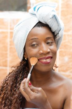 young woman applying face powder in the mirror in the bathroom.