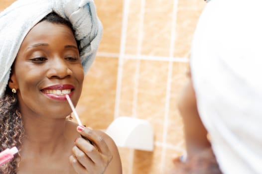 beautiful woman applying makeup in the mirror in the bathroom.