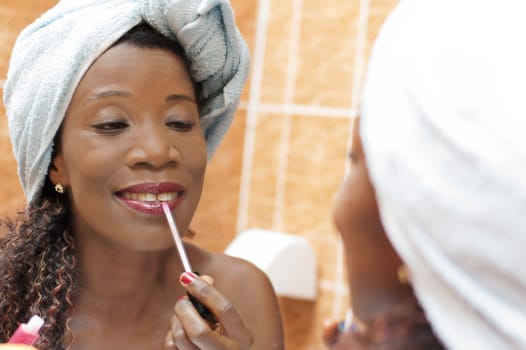 beautiful woman applying makeup in the mirror in the bathroom.