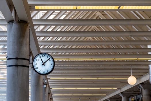 Round clock at the railway station or at the airport under the roof of metal structures for passengers looking time.
