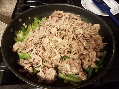 frying pan with pulled pork and green peppers on stove