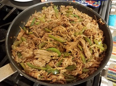 frying pan with pulled pork and green peppers on stove