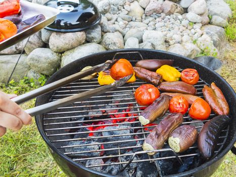 Cooking vegetables on a round grill outdoors in summer.