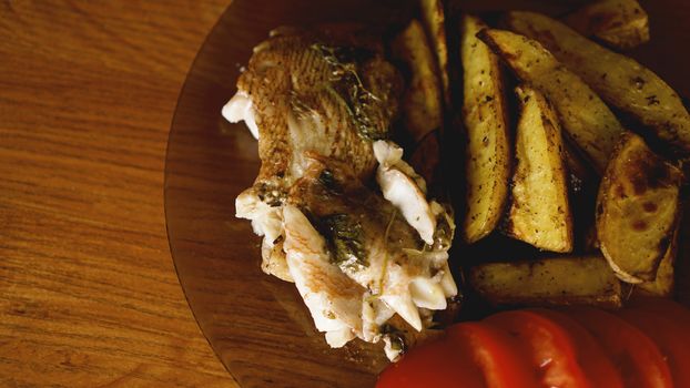 Fish dish - fried fish fillet with fried potatoes and vegetables with spices and rosemary, top view, copy space