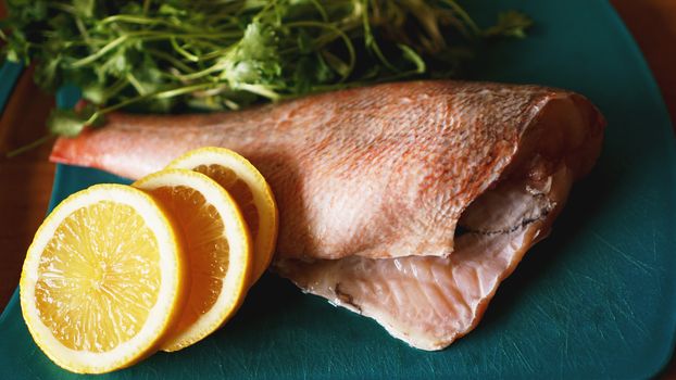 Fresh fish on a cutting board, raw cod fillets with addition of herbs and lemon