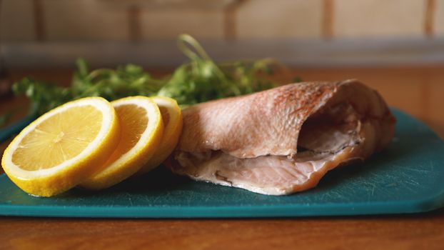 Fresh fish on a cutting board, raw cod fillets with addition of herbs and lemon