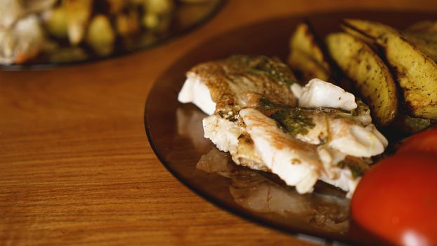 Fish dish - fried fish fillet with fried potatoes and vegetables with spices and rosemary, top view, copy space