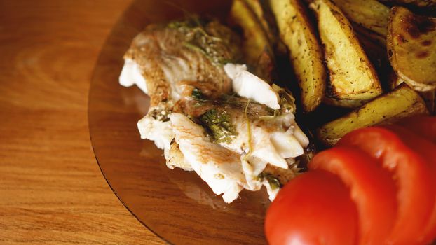 Fish dish - fried fish fillet with fried potatoes and vegetables with spices and rosemary, top view, copy space