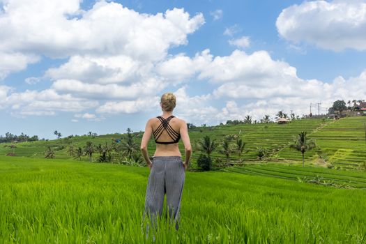 Relaxed sporty female traveler enjoying pure nature at beautiful Jatiluwih rice fields on Bali. Concept of sustainable tourism, nature enjoyment, balanced life, freedom, vacations and well being.