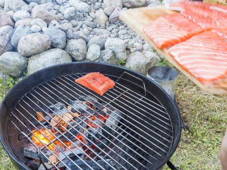 Cooking fresh salmon steak on the grill, outdoors in summer.