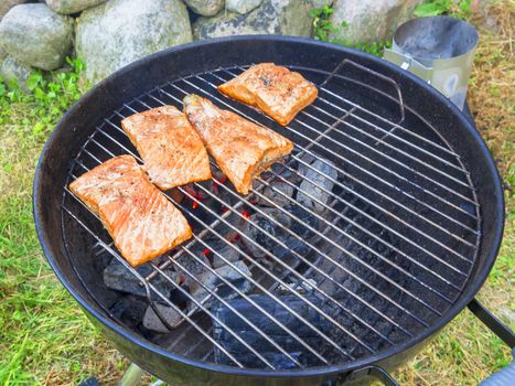 Cooking fresh salmon steaks on the grill, outdoors in summer.