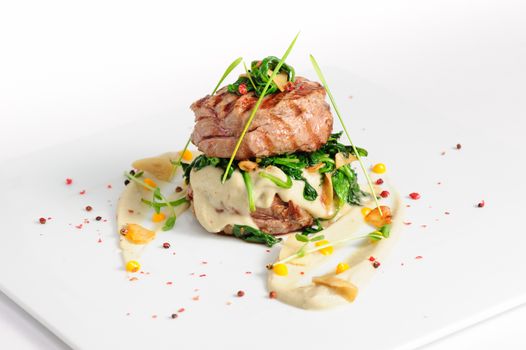 Veal medallions with spinach on white background