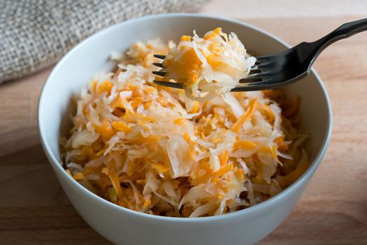 Fermented cabbage and carrots in a bowl and on a fork