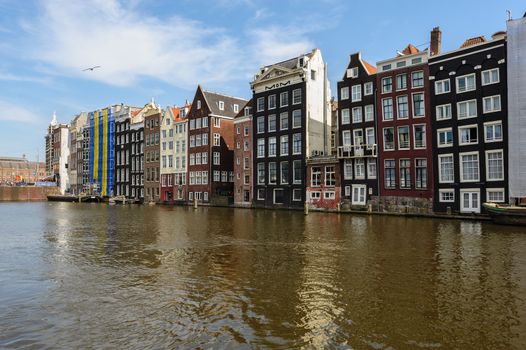 Spirngtime view of the Dancing Canal Houses of Damrak, iconic canal houses in the capital city of Amsterdam, Netherlands