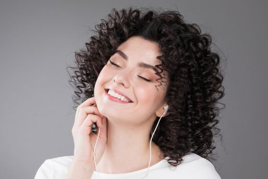 Pretty girl with curly hair listening music with her earphones