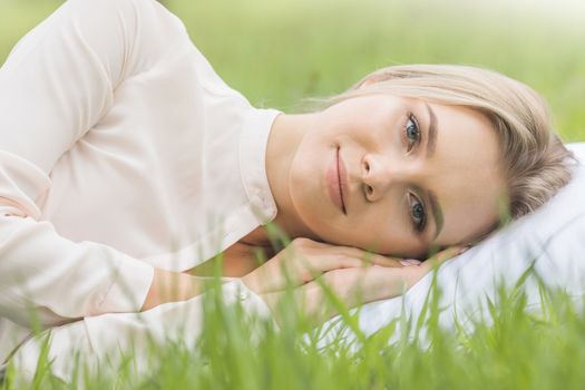 Young cute girl resting on soft pillow in fresh spring grass