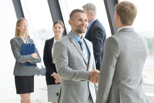 Business people shaking hands, finishing up a meeting in modern office