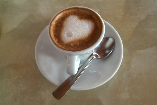 white coffee cup with heart shape made of foam in italian bar.