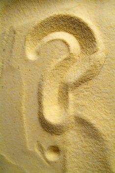 question mark sign handwritten in yellow sand beach