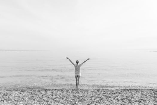 Happy Carefree Woman Enjoying Late Afternoon Walk on White Pabbled Beach in Summer.