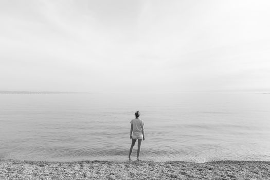 Happy Carefree Woman Enjoying Late Afternoon Walk on White Pabbled Beach in Summer.