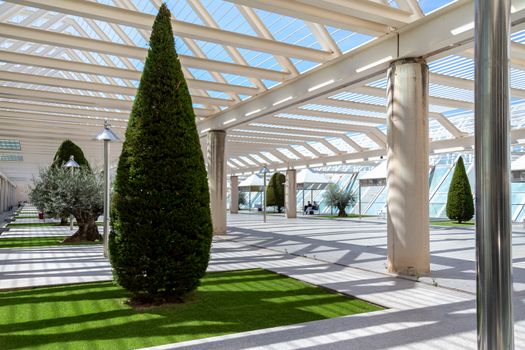 The courtyard at the airport, a place to smoke and wait for boarding outdoors. Modern architecture with metal columns and beams. Decorated with conifers, small lawns and gazebo.