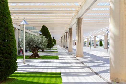 The courtyard at the airport, a place to smoke and wait for boarding outdoors. Modern architecture with metal columns and beams. Decorated with conifers, small lawns and gazebo.