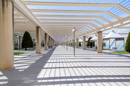 The courtyard at the airport, a place to smoke and wait for boarding outdoors. Modern architecture with metal columns and beams. Decorated with conifers, small lawns and gazebo.