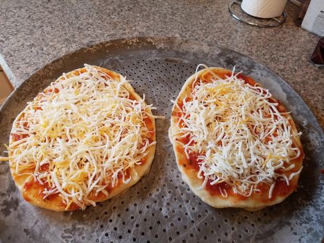 two personal size or mini pizzas on baking tray or sheet