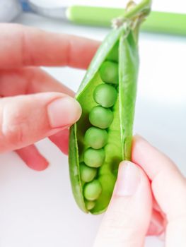 Young woman shelling fresh green peas. Healthy food and lifestyle