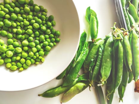 green peas freshly removed from the pod on a white plate. Agriculture and vegetables. Healthy food and lifestyle.