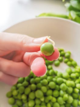 Woman's fingers holding green pea. Healthy food and lifestyle