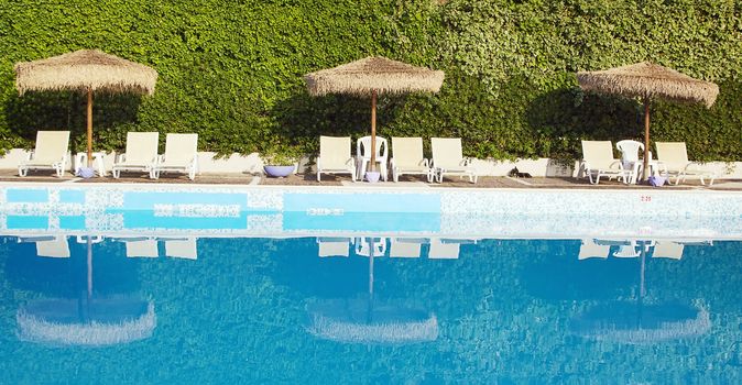 Swimming pool area of hotel with sun umbrella and beach chair