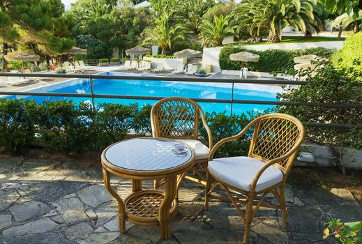 table and chairs for rest overlooking the pool in the hotel territory