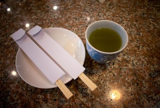 Cup of Green Tea and Two pairs of Displosable Chopsticks on a Marble Table