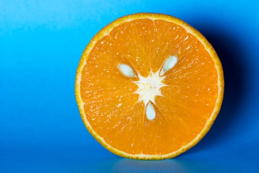 Fresh and juicy orange with seeds on light blue background.