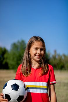 Little girl playing soccer on grassy esplanade