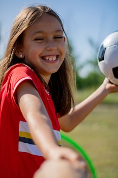 Little girl playing soccer on grassy esplanade