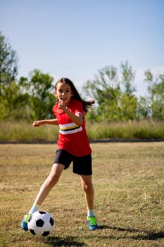 Little girl playing soccer on grassy esplanade