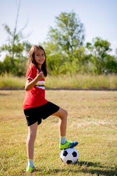 Little girl playing soccer on grassy esplanade