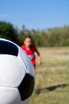 Little girl playing soccer on grassy esplanade