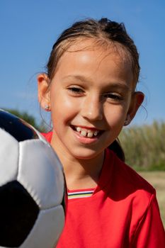 Little girl playing soccer on grassy esplanade