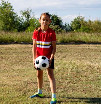 Little girl playing soccer on grassy esplanade