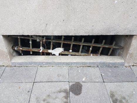 grey cement wall and tiles and broken iron bars on window with trash