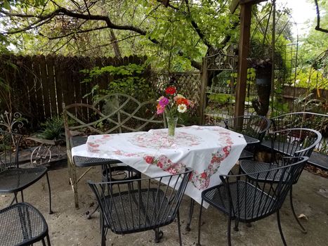 metal chairs and table with tablecloth and flowers in vase